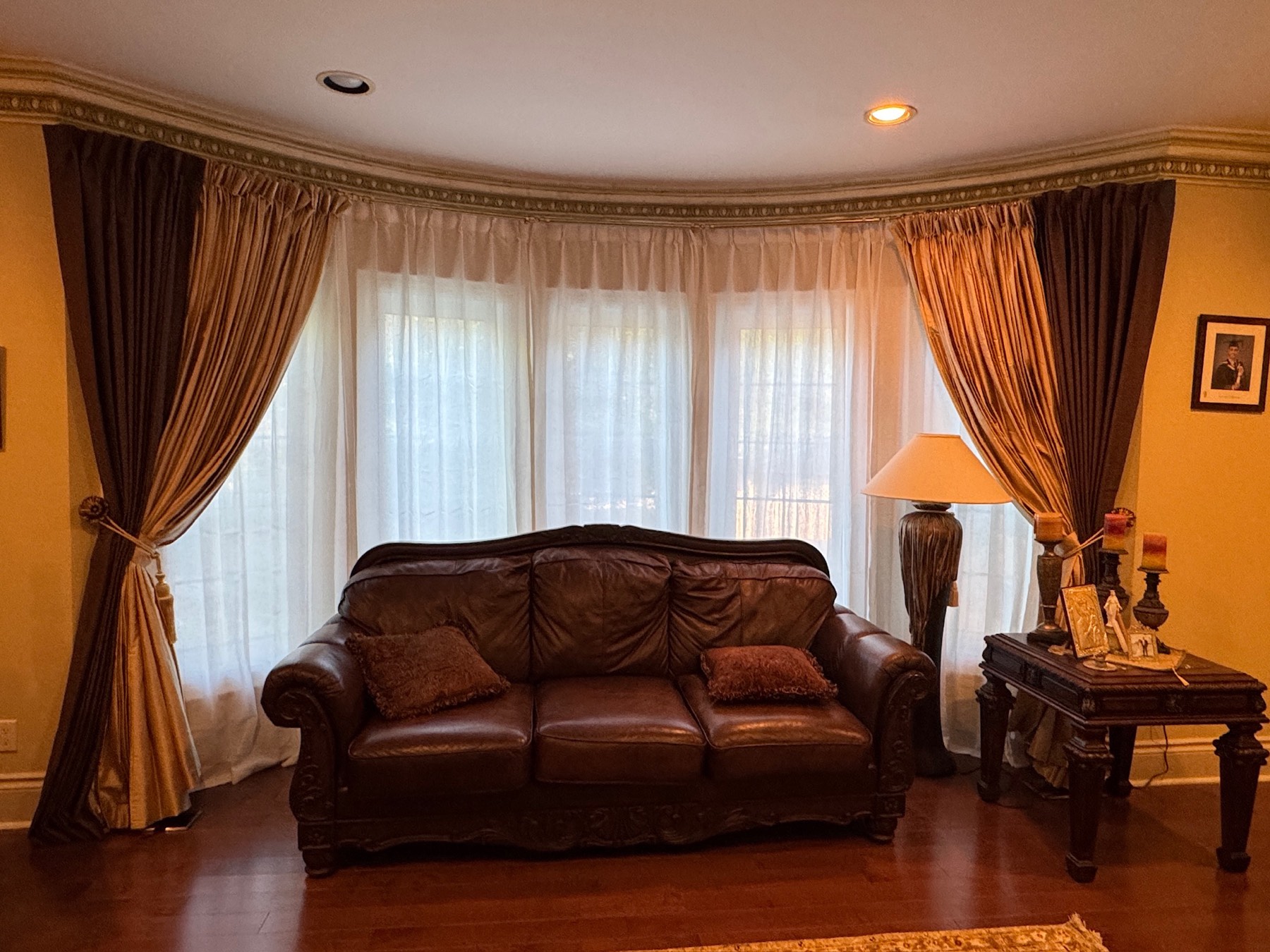 Full-length drapery with sheers and tiebacks across a curved living room bay window