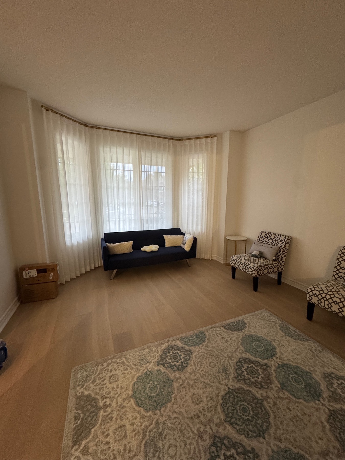Floor-length sheers on a curved bay window track in a guest room